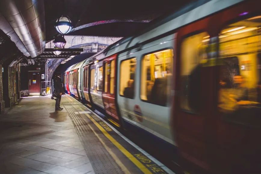 Andén de metro con un tren en marcha y una persona esperando