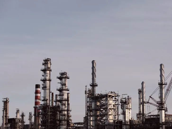 Instalación industrial con torres y chimeneas bajo un cielo gris